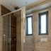 Plakias Resorts bathroom with glass shower, wall-mounted toilet and small windows in Plakias
