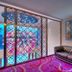 One One Bangkok Hotel room with tufted black sofa, colorful wall art, and patterned glass window