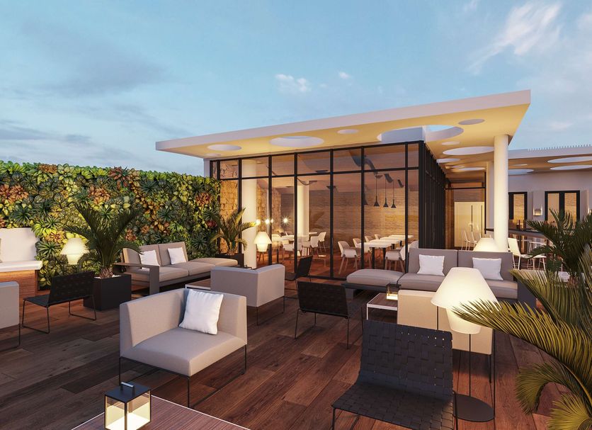 abba Sevilla rooftop terrace with lounge seating, glass-walled dining area and city skyline at dusk