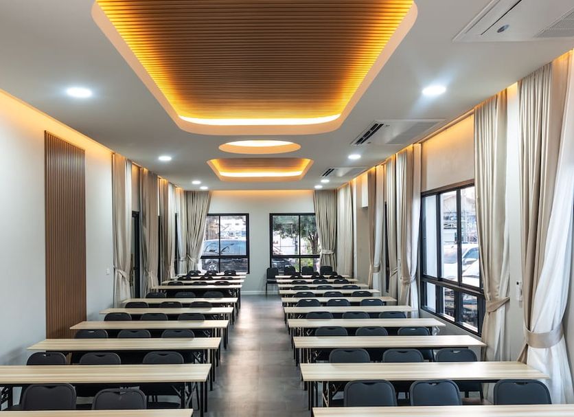 Khunyuw Hotel in Fang meeting room with rows of tables, chairs, and large windows with curtains