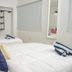 Casa Toñita in Levittown: bright twin bedroom with white beds, blue pillows and wall-mounted shelves