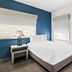 SureStay by Best Western Santa Monica guest room with queen bed, blue accent wall, and windows with blinds