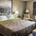 Super 8 by Wyndham Knoxville guest room with king bed, lamps, armchair and scenic wall art