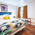 Stonewall Motor Lodge guest room with bed, patterned throw, window and wooden chairs in Stonewall
