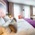 Leonardo Hotel Munich City South guest room with king bed, TV, desk, and city-view window