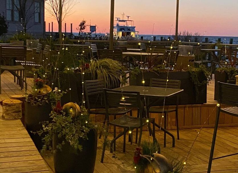 Sunset view from Tilghman Island Inn terrace in Tilghman Island with outdoor tables, planters, and water beyond
