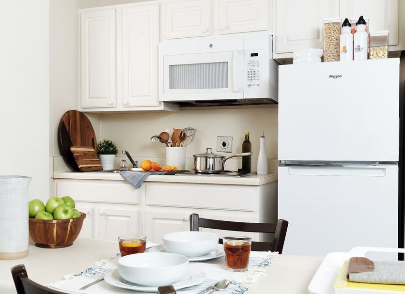 Intown Suites Extended Stay Huntsville AL - NASA kitchen with white cabinets, fridge, microwave and dining table
