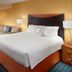Fairfield Inn & Suites by Marriott Clarksville guest room with king bed, sofa, armchair and lamps