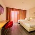 Una Hotels Le Terrazze Treviso Hotel & Residence room in Villorba with two beds, desk, wall TV, and balcony curtains