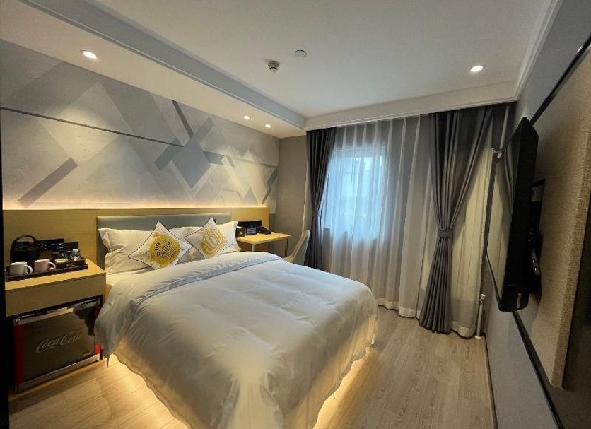 Mingcheng Hotel Beijing guest room with bed, bedside tables, wall-mounted TV and window curtains