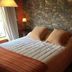 Refugio Del Pintor in Tilcara guest room with stone wall, double bed and warm bedside lamps