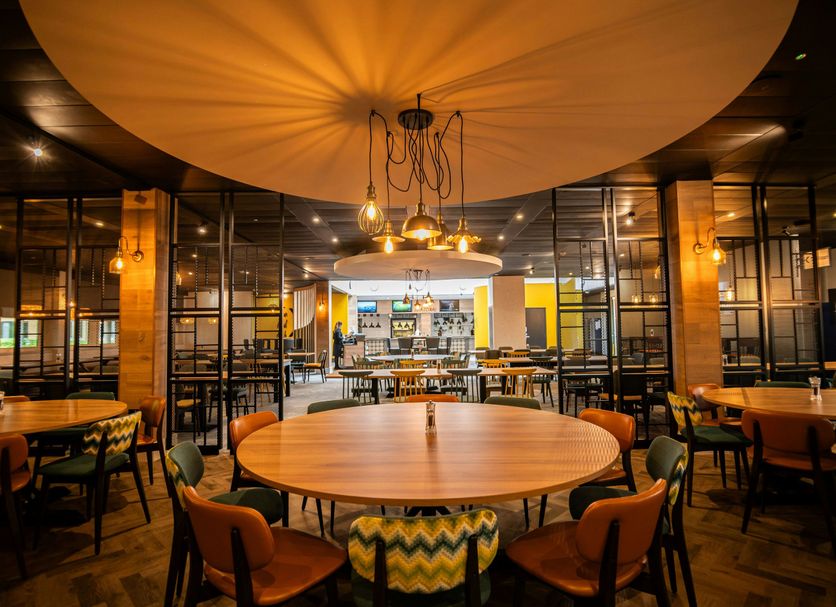 Kents Hill Park Training & Conference Centre in Milton Keynes dining room with round tables and warm lighting