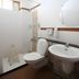 Hotel De Ecobiz in Ahmedabad bathroom with shower, toilet, sink, and round wall mirror