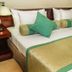 Oak Ray Heritage Hotel in Kandy guest room with a neatly made bed, green pillows, and bedside lamp