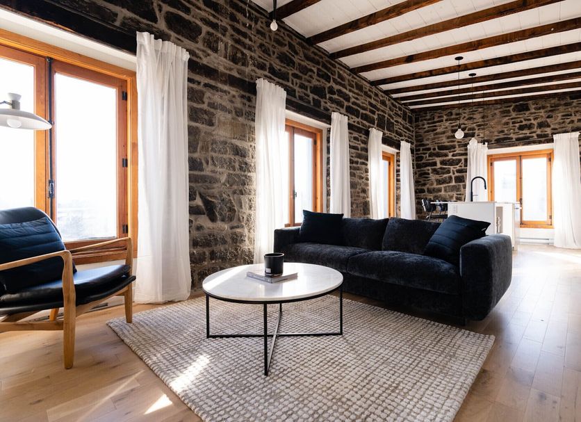 Maison Place Royale by Luxury In Transit in Montreal, stone-walled suite with sofa, armchair and round coffee table