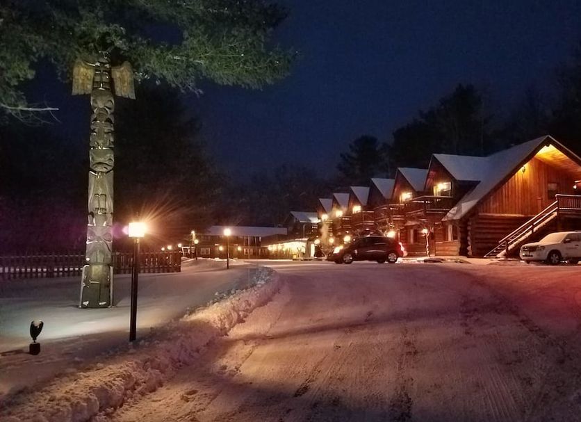 Nootka Lodge in Woodsville at night, with snow-covered driveway and warmly lit cabins