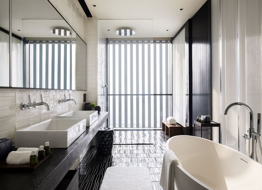 Upper House Shanghai bathroom with freestanding tub, double vanity, and striped city-view windows