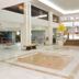 Hotel Embaixador in Porto Alegre lobby with high ceilings, seating, and stairs to an upper level