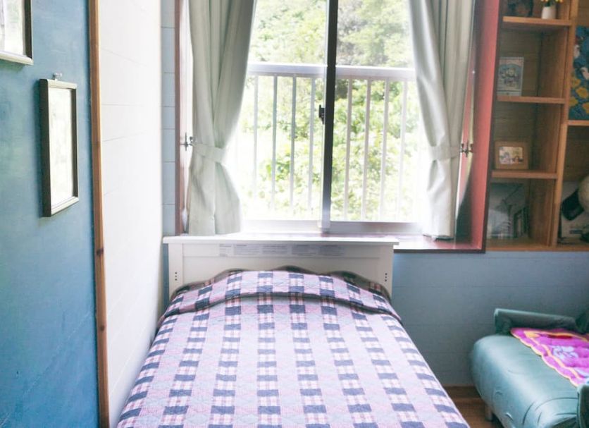 Guest House Amakara Okinawa in Nago: small room with single bed, window and shelving
