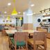Bloom Hotel - Sg Highway, Ahmedabad dining area with wooden tables, green seating and yellow pendant lights