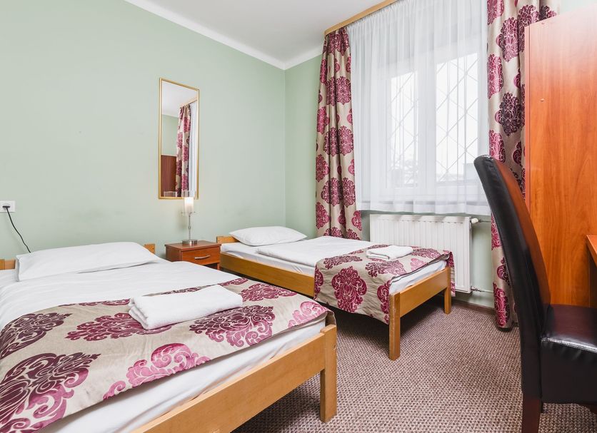 Hostel Bialy Dom in Krakow: twin bedroom with two single beds, desk, chair, and floral curtains