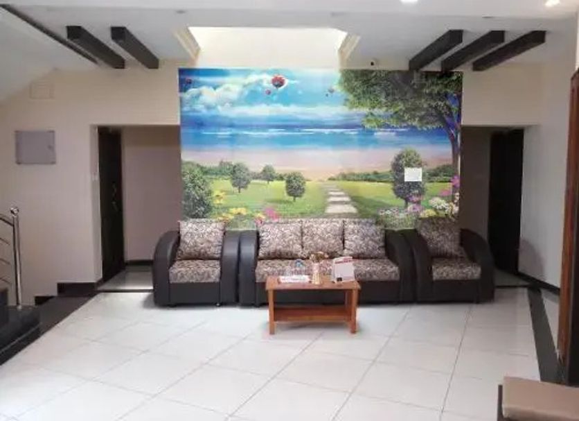 Sr Residency in Tiruchirappalli lobby with sofa seating and scenic wall mural