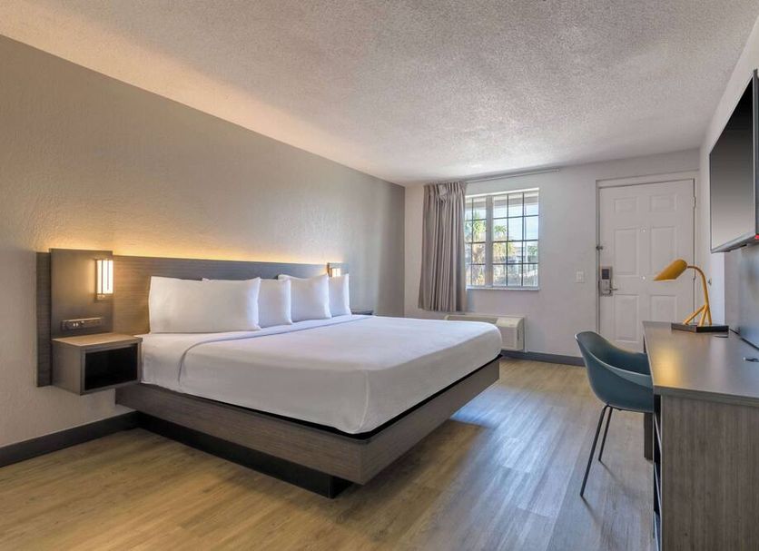 Motel 6 Ocala Conference Center guest room with king bed, desk, TV and window in Ocala