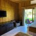 La Ensenada Beach Resort in Tela: wood-paneled room with TV, chairs, bed, and garden-view patio door