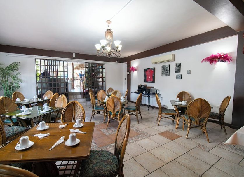 The Chancellor Hotel in Port of Spain dining room with wicker chairs, set tables, and chandelier