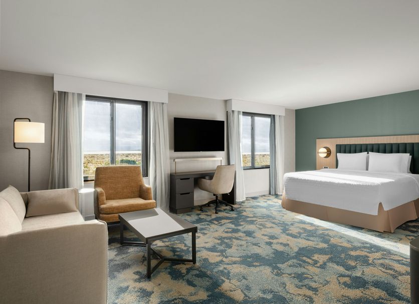 Hampton Inn & Suites Oakland Airport-Alameda guest room with king bed, sofa, desk, and large windows in Alameda