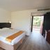 Gem Beach Resort in Kuala Terengganu guest room with king bed, armchair, and balcony door open to greenery