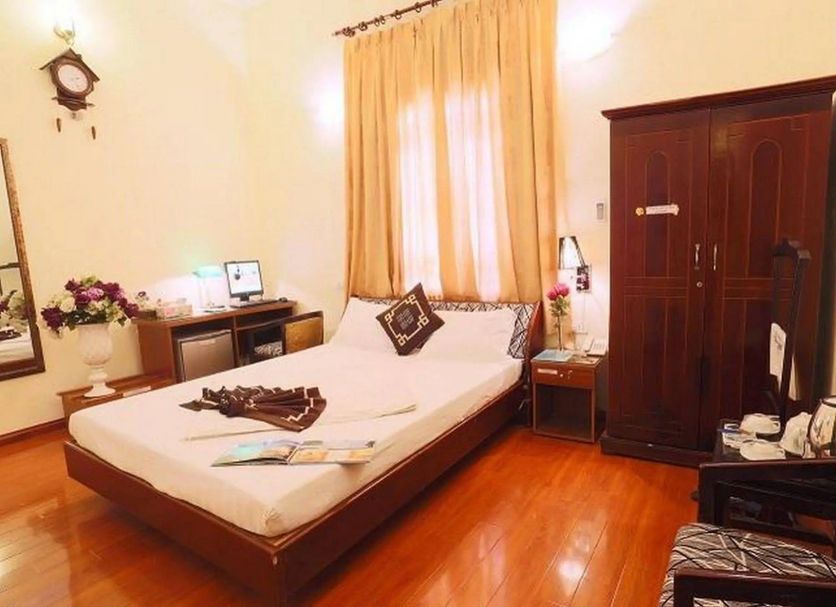 A25 Hotel Mai Hac De guest room in Hanoi with a bed, desk, wardrobe and polished wood floor.