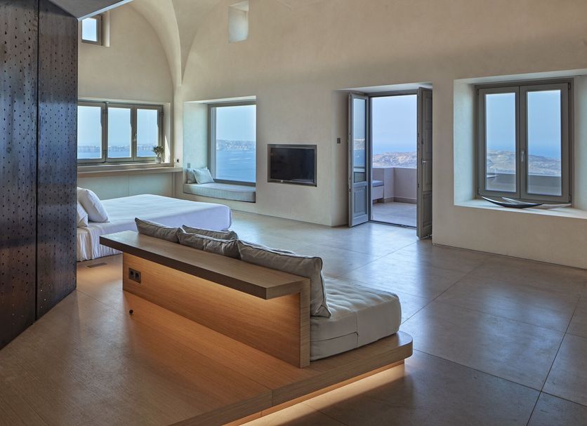 Villa Bordeaux, Thera: bright suite with sea-view windows, lounge seating, and balcony door
