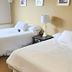 The Medicine Hat Villa room with two white beds, bedside lamp, and window in Medicine Hat