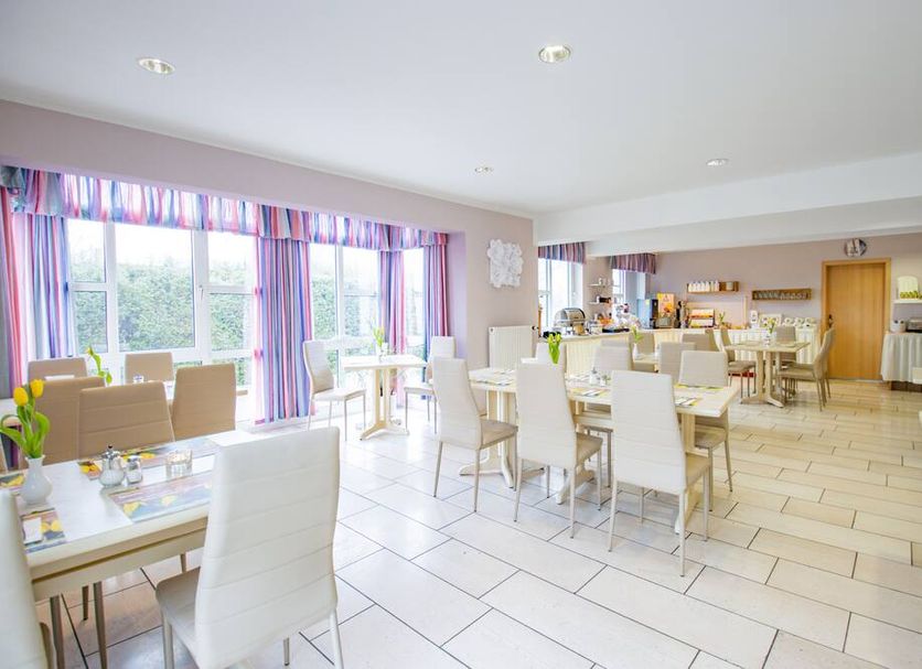 Hotel garni Zwickau-Mosel in Glauchau breakfast room with white tables, chairs and large windows