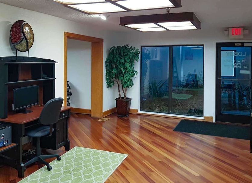 Motel 6 Little Rock, Ar - Airport lobby with wood floors, desk area, potted plant and glass entrance