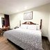 Budget Inn Northport guest room with queen bed, desk, and wood-look flooring in Northport