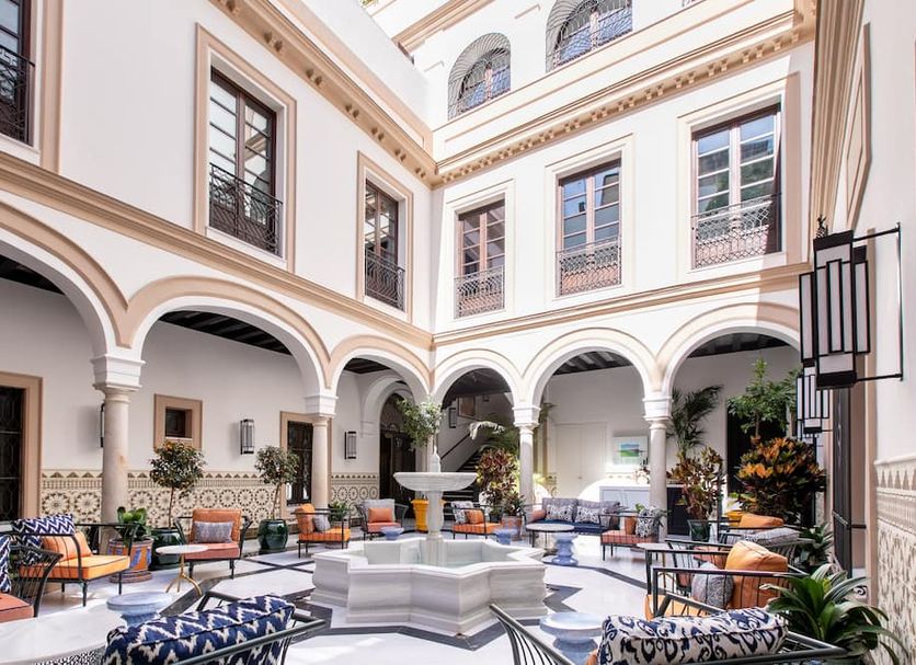 Hotel Casa Palacio Don Ramón in Seville courtyard with arched colonnades, fountain, and seating