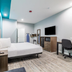 Scottish Inns & Suites - Kingwood room in Humble with bed, desk, TV and teal accent wall