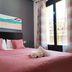 Flats Friends Plaza de la Reina room in Valencia with pink bed, rolled towels, and city-view windows