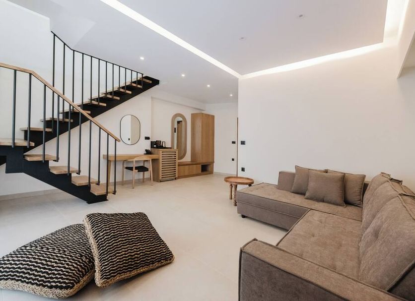 Evexia boutique hotel & spa in Nea Kydonia: modern suite with sectional sofa, staircase, and vanity area