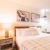 Innsbruck Inn at Stowe guest room with king bed, bedside lamps, wall art, and clothes rack