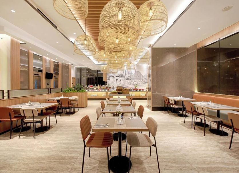Aston Inn Pantai Losari Makassar dining area with tables and woven pendant lights in Makassar