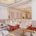 Hotel Ambica Empire Chennai banquet hall with white chair covers, chandeliers and ornate ceiling