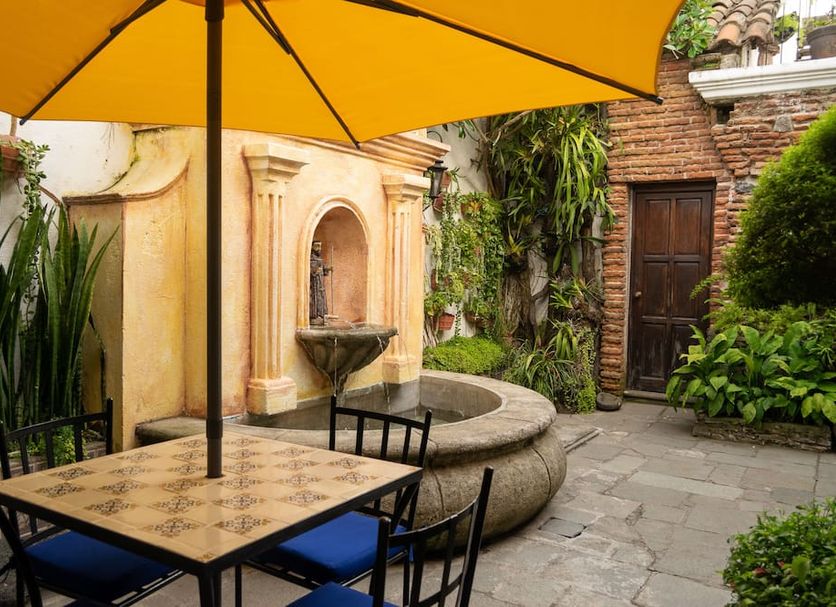 Hotel La Villa Serena in Antigua courtyard with yellow umbrella, fountain, and stone seating