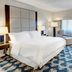 Sheraton Eatontown Hotel guest room with king bed, chaise lounge and large window with curtains in Eatontown