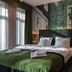 Oliva Hotel Veszprém guest room with double bed, green blanket, and wall mural headboard