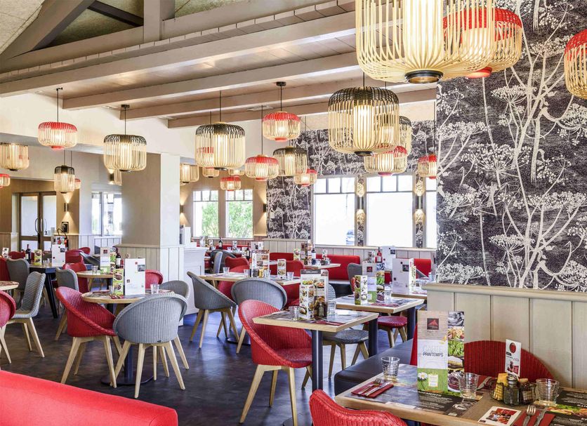 Ibis Budget Bayonne dining area with red and gray chairs and patterned wall decor