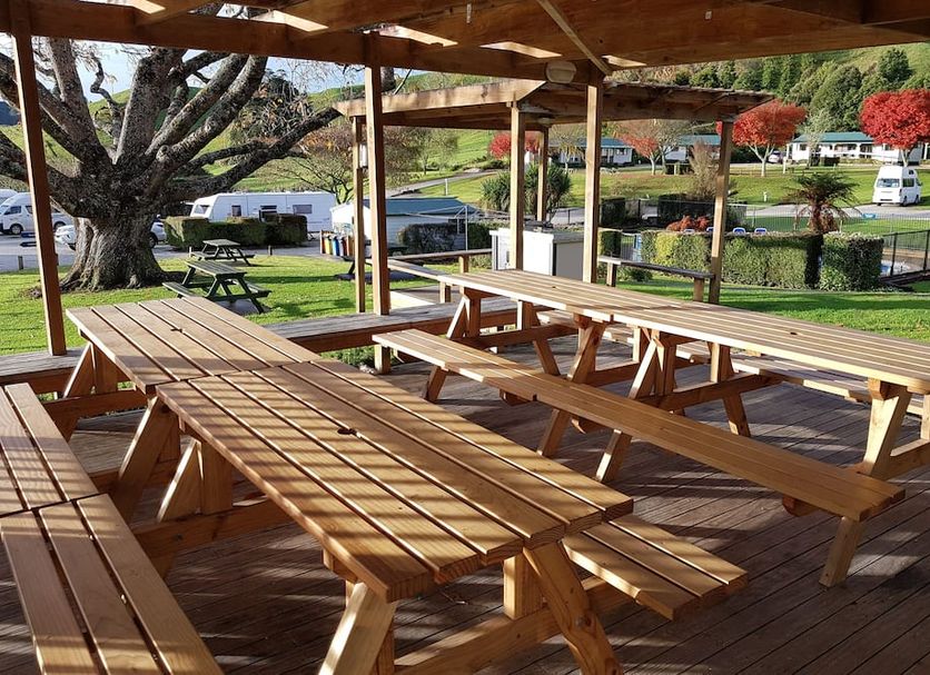Waitomo Top 10 Holiday Park outdoor picnic shelter with wooden tables and grassy park views