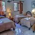 Hotel Jaguar Inn Tikal guest room with four twin beds, bedside lamps, and tiled floor